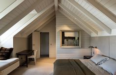 a bed sitting under a window in a bedroom next to a wooden desk and chair