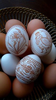 some eggs are sitting in a basket on the table and one is painted with an image of a bird