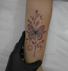 a woman's arm with a butterfly and flower tattoo on the left inner forearm