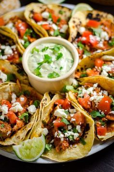 an assortment of tacos on a plate with salsa and sour cream in the middle