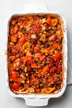 a casserole dish filled with ground beef, tomatoes, corn and carrots