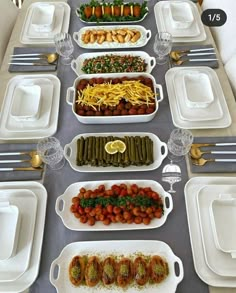 a long table is set up with many dishes and silverware, including salads