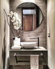 a bathroom sink sitting under a round mirror