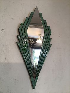 a mirror mounted to the side of a white wall next to a plant in a vase