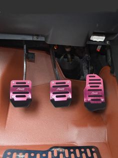 three pink pedals in the center console of a car