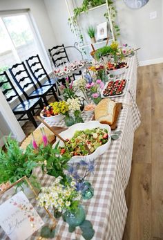 a long table with many different types of food on it and flowers in vases