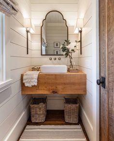 a bathroom with a sink, mirror and two wicker baskets on the floor in front of it