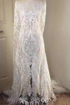 the back of a white wedding dress on display in front of a door with lace