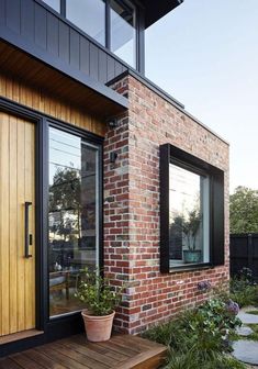 a brick house with black windows and wooden steps