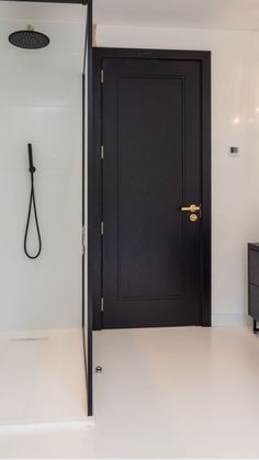 a bathroom with a black door and white walls