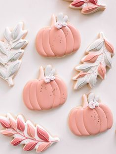 decorated cookies with pink frosting and white icing are arranged in the shape of pumpkins