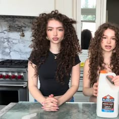 two young women standing in front of a counter top with hair dryer on it