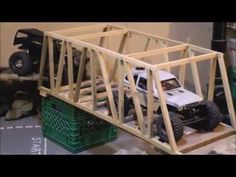 a toy truck driving across a bridge made out of wooden planks and plastic crates