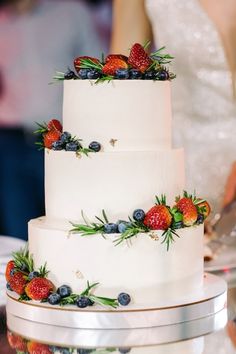 a wedding cake with berries and blueberries on it