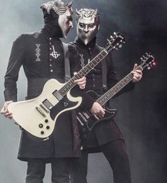 two men dressed in black and white are holding guitars