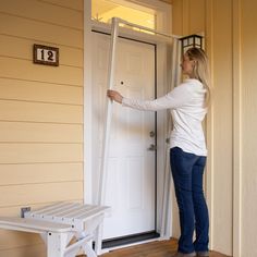 a woman standing in front of a door holding onto the side of a white door