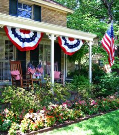 an american flag bunting on the front porch of a house with flowers and chairs