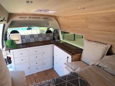 the interior of a camper van with white cabinets and wood flooring is shown