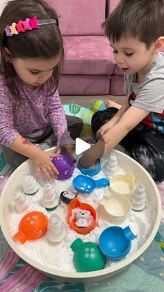 two young children are playing with sand and water