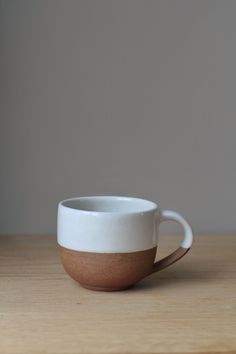 a white and brown coffee cup sitting on top of a wooden table