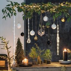 a table topped with lots of christmas decorations and lit candles next to potted plants