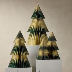 three folded paper christmas trees sitting on top of each other in front of a wall