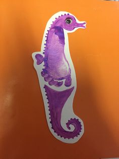 a purple and white sea horse sticker on an orange background