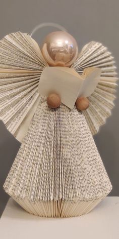 an origami angel reading a book with a golden sphere on its head and wings