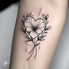 a heart shaped tattoo with flowers and leaves on the side of the arm is shown