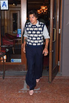 a man walking out of a building wearing a blue and white sweater with clouds on it