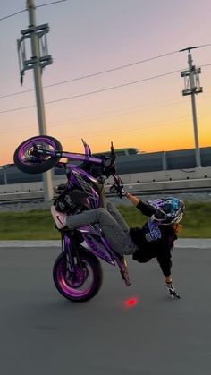 a person on a motorcycle doing a wheelie in the air with their hand up