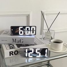 two alarm clocks sitting on top of each other next to a cup of coffee and books