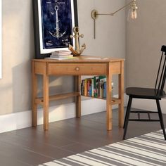 a wooden desk with a chair next to it and a framed poster on the wall