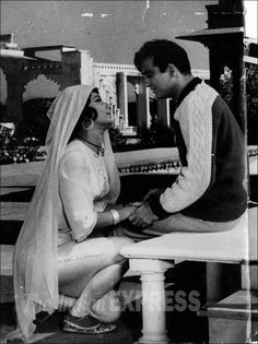 a man sitting next to a woman on top of a white bench in front of a building