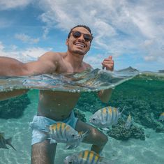 a man under water giving the thumbs up sign with fish around him and in the foreground