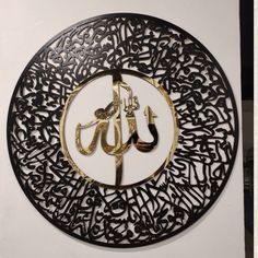 an arabic calligraphy in gold and black on a circular metal plaque with the word,