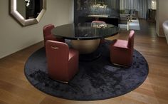 a dining room table with red chairs and a round rug on the floor in front of it