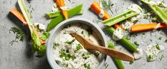 a bowl filled with dip surrounded by celery and carrots