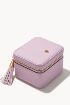 a small pink case with a tassell on the side and gold zippers