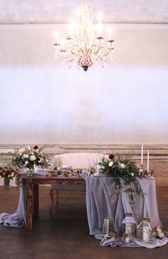 the table is set up with flowers and candles for an elegant wedding reception in front of a chandelier