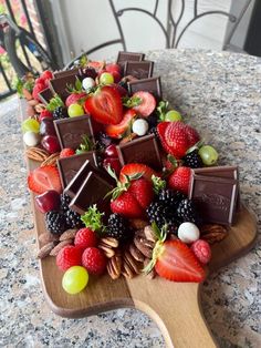 a wooden platter filled with chocolate covered strawberries and other fruit on top of a table