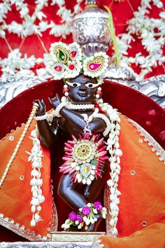 an idol is sitting in the middle of a red bowl with white flowers on it