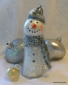 a glass snowman sitting next to two ornaments