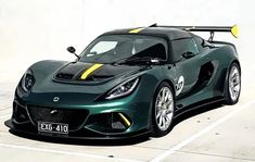 a green sports car with yellow stripes parked in a parking lot next to a white wall