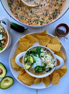 a bowl of soup with tortilla chips and avocado on the side