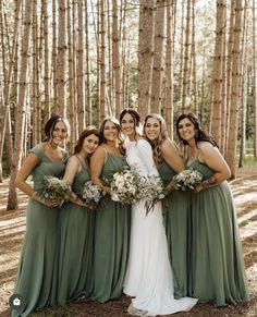 a group of women standing next to each other in front of trees