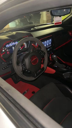 the interior of a sports car with red and black leather seats, steering wheel and dashboard