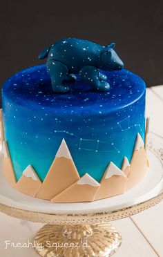 there is a blue cake with an animal on top and stars in the sky above it