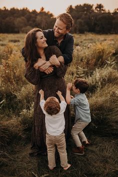 an adult and two children standing in a field with their arms around each other as the sun sets