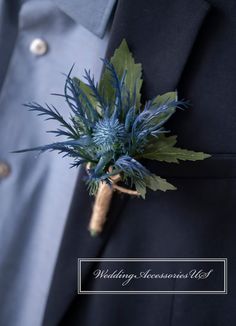 a boutonniere with blue flowers and greenery on it's lapel